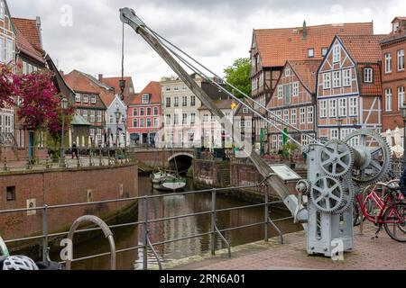 Vecchia gru e sullo sfondo case medievali sul canale di Stade e nave a vela museo Willi, Hansehafen, Stade, bassa Sassonia, Germania Foto Stock