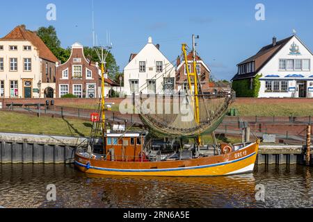 Taglia granchio con rete di granchio nel porto di Greetsiel con case storiche, Greetsiel, Frisia orientale, Mare del Nord, bassa Sassonia, Germania Foto Stock