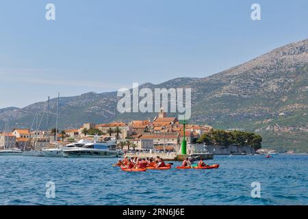 KORCULA, CROAZIA - 24 giugno 2019: I turisti in kayak di fronte al panorama della penisola con l'antica città sullo sfondo. Foto Stock