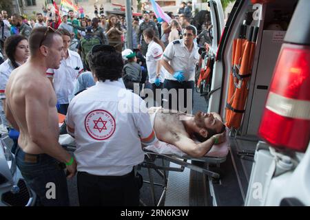 (150730) -- GERUSALEMME, 30 luglio 2015 -- le persone trasportano un giovane israeliano ferito in un attacco di pugnalaggio su un'ambulanza durante l'annuale sfilata del gay Pride a Gerusalemme, il 30 luglio 2015. Sei persone sono state pugnalate alla parata annuale del gay Pride di Gerusalemme giovedì, in uno dei più gravi attacchi alla comunità gay in Israele, hanno detto a Xinhua funzionari e testimoni oculari israeliani. Un portavoce della polizia ha detto che l'assalitore è stato catturato e identificato come Yishai Schlissel, un uomo ebreo ultra-ortodosso che ha compiuto un attacco simile nel 2005, ferendo tre persone. Schlissel è stato rilasciato solo dalla prigione Foto Stock