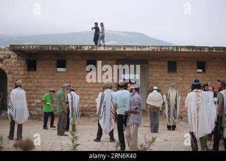 (150730) - GERUSALEMME, 30 luglio 2015 -- i coloni ebrei israeliani pregano nell'insediamento di sa-Nur nella Cisgiordania settentrionale, il 30 luglio 2015. Giovedì le forze di sicurezza israeliane hanno evacuato circa 200 coloni dal sito dell'ex insediamento illegale di sa-Nur nella Cisgiordania settentrionale, ha affermato un portavoce militare in una dichiarazione. Da quando sa-Nur è stata evacuata come parte del piano di disimpegno del 2005 da Gaza, gli ex residenti di sa-Nur hanno fatto diversi tentativi per ricostruire il loro insediamento. /MIRI TZACHI) ISRAELE FUORI MIDEAST-CISGIORDANIA-INSEDIAMENTO ILLEGALE-EVACUAZIONE JINI PUBLICATIONXNOTXINXCH Foto Stock