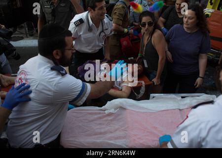 (150730) -- GERUSALEMME, 30 luglio 2015 -- le persone trasportano un giovane israeliano ferito in un attacco di pugnalaggio su un'ambulanza durante l'annuale sfilata del gay Pride a Gerusalemme, il 30 luglio 2015. Sei persone sono state pugnalate alla parata annuale del gay Pride di Gerusalemme giovedì, in uno dei più gravi attacchi alla comunità gay in Israele, hanno detto a Xinhua funzionari e testimoni oculari israeliani. Un portavoce della polizia ha detto che l'assalitore è stato catturato e identificato come Yishai Schlissel, un uomo ebreo ultra-ortodosso che ha compiuto un attacco simile nel 2005, ferendo tre persone. Schlissel è stato rilasciato solo dalla prigione Foto Stock