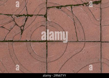 Close-up of broken and weathered red square paving stones or blocks with geometric shapes outdoors, viewed from above. Full frame textured background. Stock Photo