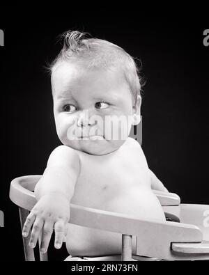 1950S DIFFIDENTE IL BAMBINO CHE SIEDE IN SEGGIOLONE GUARDANDO DIETRO DIETRO ALLE SPALLE - B5447 HAR001 HARS HEALTHINESS HOME LIFE COPY SPAZIO ESPRESSIONI DI TRASPORTO A MEZZA LUNGHEZZA TURBATI B&W PREOCCUPATI OBIETTIVI DI TRISTEZZA TENTAZIONE AFFAMATO FELICITÀ UMORE CRESCITA CONCETTUALE GLUM SEGGIOLONE GIOVANI INFELICI DIFFIDENTE BAMBINA NERA E BIANCA ETNIA CAUCASICA HAR001 VECCHIO STILE INCERTO Foto Stock