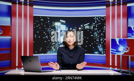 Emittente mediatica che organizza talk show a tarda notte, discutendo di importanti eventi globali in un programma televisivo in diretta. Donna asiatica che lavora come giornalista per il segmento tv dell'intrattenimento. Foto Stock