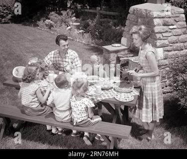 FAMIGLIA DEGLI ANNI '1960 CHE MANGIA AL TAVOLO DA PICNIC CHE CUCINA SUL STONE GRILL NEL CORTILE SUL RETRO, MADRE, PADRE E 4 BAMBINI - C3898 HAR001 HARS NOSTALGICO 4 COMMUNITY STONE, SUBURBANO, MADRI, VECCHIO TEMPO, AFFOLLATO, NOSTALGIA, FRATELLO, VECCHIA SORELLA DI MODA, LAVORO DI SQUADRA IN STILE GRILL GIOVANILE FIGLI LIMONATA STILE DI VITA FEMMINE CONIUGI FRATELLI CONIUGI MARITI SALUBRITÀ VITA DOMESTICA 6 COPIA SPAZIO AMICIZIA FULL-LENGTH SIGNORE HALF-LENGTH FIGLIE PERSONE MASCHI SEI FRATELLI SORELLE PADRI B&W IN ESTATE GRIGLIANDO FELICITÀ ANGOLO ALTO TEMPO LIBERO VITTORIA E PAPÀ ECCITAZIONE HAMBURGER FRATELLO ANGURIA ELEGANTE SUPPORTARE LA COOPERAZIONE DEI BAMBINI Foto Stock