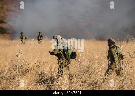 (150820) -- GERUSALEMME, 20 agosto 2015 -- soldati israeliani pattugliano vicino al fumo di un incendio causato da un attacco missilistico sulle alture del Golan vicino al confine libanese, il 20 agosto 2015. Le forze di difesa israeliane (IDF) spararono artiglieria in Siria e trasportarono attacchi aerei in risposta a una raffica di razzi atterrati in precedenza nel nord di Israele, l'unità portavoce dell'IDF ha confermato in una dichiarazione. La dichiarazione dell'IDF ha confermato di aver sparato artiglieria e attacchi aerei contro la Siria, aggiungendo che ha colpito diverse posizioni dell'esercito siriano, e ha incolpato la Jihad islamica, con il sostegno dell'Iran e del gov siriano Foto Stock