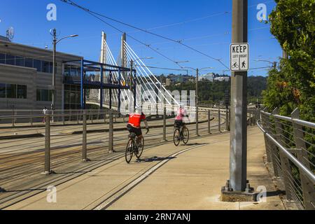 Uomo e donna in bicicletta al Bridge of the People, al Tilikum Crossing sul fiume Willamette presso il Portland Oregon Waterfront Foto Stock