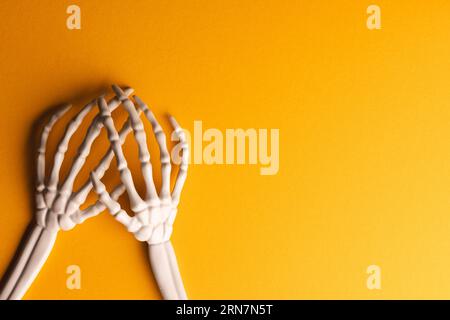 Mani scheletro in plastica con spazio per la copia su sfondo giallo Foto Stock