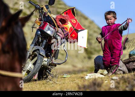 (150921) -- URUMQI, 2015 -- foto scattata il 17 settembre 2015 mostra un bambino di quattro anni che viaggia con la sua famiglia di pastori impegnati a trasferire le loro pecore e mucche ai pascoli invernali nella prefettura di Altay, nella regione autonoma di Xinjiang Uygur, nella Cina nordoccidentale. Quando l'estate è giunta al termine, le famiglie locali di pastori kazak hanno iniziato a spostare le loro mandrie nei pascoli invernali. (Wjq) CINA-XINJIANG-ALTAY-PASTORI-PASCOLI INVERNALI (CN) ShenxQiao PUBLICATIONxNOTxINxCHN Urumqi 2015 la foto scattata IL 17 settembre 2015 mostra un bambino di quattro anni in viaggio con la sua famiglia di pastori che sono impegnati a trasferire Foto Stock