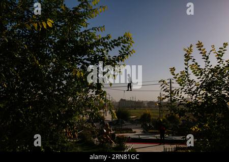 (150930) -- KASHGAR, 30 settembre 2015 -- An acrobat Walks on a tightrope in the Old Town of Kashgar, North West China S Xinjiang Uygur Autonomous Region, 21 settembre 2015. Kashgar, la città più occidentale della Cina, è stata per secoli il centro della civiltà uigura, un luogo dove le persone si sono riunite per commerciare e diffondere l'apprendimento islamico, sulle rotte carovane dall'Europa e dalla Persia alla Cina. (lfj) CHINA-XINJIANG-KASHGAR-OLD TOWN (CN) ZhangxCheng PUBLICATIONxNOTxINxCHN Kashgar settembre 30 2015 alle passeggiate in acrobata SU un Tightrope nella città vecchia di Kashgar nella regione autonoma di Xinjiang Uygur della Cina nordoccidentale Foto Stock