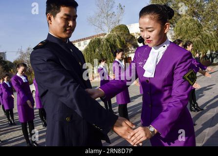 (151018) -- URUMQI, 18 ottobre 2015 -- una hostess di treni interurbani corregge l'azione del suo collega durante un addestramento a Urumqi, capitale della provincia dello Xinjiang della Cina nord-occidentale, 18 ottobre 2015. Un nuovo treno intercity che collega Urumqi e Korla sarà operativo dal 20 ottobre con 121 membri del personale provenienti da diversi gruppi etnici. ) (zhs) CHINA-XINJIANG-NEW INTERCITY TRAIN (CN) ZhaoxGe PUBLICATIONxNOTxINxCHN Urumqi Ott 18 2015 a Inter-City Train Stewardess corregge l'azione del suo collega durante un addestramento nella provincia dello Xinjiang della capitale Urumqi della Cina nord-occidentale Ott 18 2015 a New Inter-City tra Foto Stock