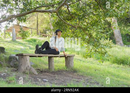 Donna seduta su una panchina di legno che ammira la natura. Ritratto di una donna che gode della natura. Foto Stock