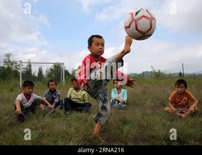 Un allievo lancia un calcio nel cielo alla Hongxing Village Elementary School a Nanmu Township di Youyang tu e Miao Autonomous County, a sud-ovest della Cina, Chongqing, 23 settembre 2015. La Hongxing Village Elementary School, che ha solo 12 alunni di primo grado e un insegnante, è stata a lungo mancanza di strutture sportive. Un'organizzazione di beneficenza in aprile ha contribuito a palloni, gol e recinzioni di campo alla scuola, che hanno portato gioia agli alunni. ) XINHUA CHINA PHOTOS OF THE YEAR YangxMin PUBLICATIONxNOTxINxCHN a Pupil Kicks a Football into the Sky ALLA Hong Xing Village Elementary School di Nanm Foto Stock