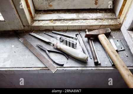 Riparazione del vecchio finestrino danneggiato o smontaggio prima di installare il nuovo primo piano. Riparazione di un telaio di una finestra, utilizzando strumenti per la ristrutturazione di vecchie finestre Foto Stock