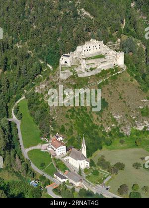 VISTA AEREA. Castello di Montechiaro o Schloss Lichtenberg (in tedesco) affacciato su una chiesa parrocchiale. Trentino-alto Adige, Italia. Foto Stock