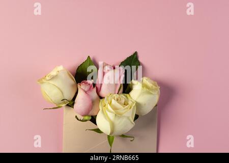 Fiori di rosa bianchi e rosa in busta marrone e spazio copia su sfondo rosa Foto Stock