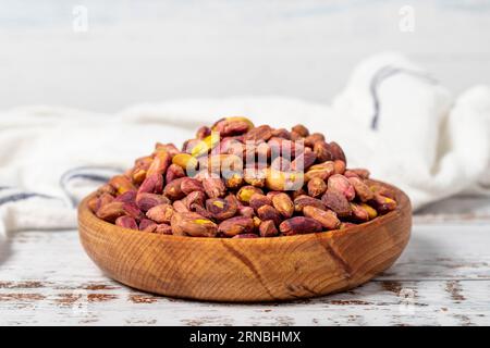 Chicchi di pistacchio in ciotola su fondo di legno. Noci per una dieta salutare e uno spuntino alternativo Foto Stock