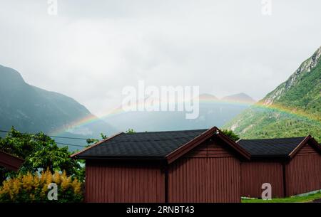 Splendido arcobaleno su un fiordo norvegese e cabine Foto Stock