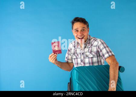 l'uomo in camicia a scacchi porta il passaporto in una mano e nell'altra la valigia pronta per partire Foto Stock