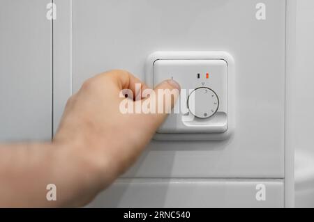 Mano d'uomo accendere con riscaldamento a pavimento. Foto Stock