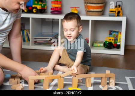 Bambino 2,5 anni che gioca con papà a blocchi di legno. Passare del tempo con i bambini. Attività educative per bambini. Stanza dei bambini. Al chiuso Foto Stock