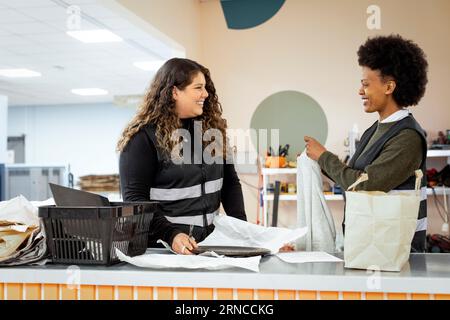 Lavoratrici felici che parlano tra loro al centro di riciclaggio Foto Stock