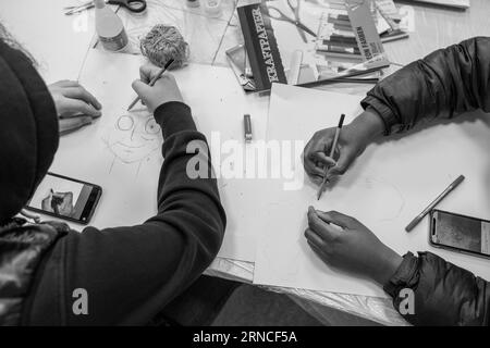 Un gruppo di adolescenti che creano con passione un disegno in bianco e nero insieme, mettendo in mostra il loro talento artistico e il loro cameratismo. Foto Stock