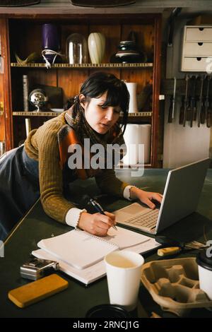 Imprenditrice che lavora su un notebook in un negozio di upcycling Foto Stock