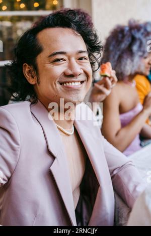 Ritratto di un uomo gay felice che indossa un blazer durante la cena nel cortile posteriore Foto Stock