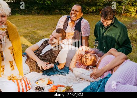 Amici della comunità LGBTQ che si godono frutta e bevande in giardino Foto Stock