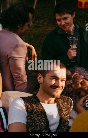 Un uomo gay sorridente con amici LGBTQ durante la cena in cortile Foto Stock