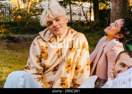 Ritratto di un uomo gay sorridente con gli amici durante la festa nel cortile posteriore Foto Stock