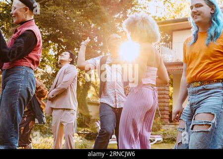 Amici felici della comunità LGBTQ che ballano insieme durante la cena in cortile Foto Stock