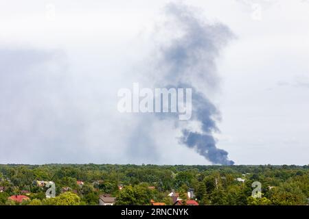 Fumo nero da un incendio che si innalza all'orizzonte. Inquinamento atmosferico causato da un disastro ecologico che finisce con un incendio. Foto scattata in una giornata nuvolosa. Foto Stock