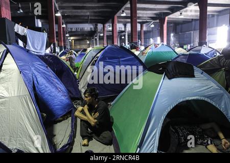 (160419) -- PIRAEUS, April 19, 2016 -- Photo taken on April 15, 2016 shows a refugee sitting among tents inside a warehouse at the Port of Piraeus behind the Passenger Terminal E1, in Piraeus, Greece. Passenger terminals at the port of Piraeus, the main gateway to the Aegean Sea islands, have turned into temporary unofficial camps sheltering more than 3,700 refugees and migrants over the past two months. With summer s tourism season on the horizon, the Greek government has stepped up its efforts to evacuate migrants from Greece s largest port by early May and transfer them to organized recepti Stock Photo