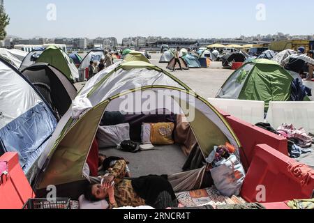 (160419) -- PIRAEUS, April 19, 2016 -- Photo taken on April 15, 2016 shows a woman checking her mobile phone outside her tent at the Passenger Terminal E2 where thousands of refugee families are stranded, in Piraeus, Greece. Passenger terminals at the port of Piraeus, the main gateway to the Aegean Sea islands, have turned into temporary unofficial camps sheltering more than 3,700 refugees and migrants over the past two months. With summer s tourism season on the horizon, the Greek government has stepped up its efforts to evacuate migrants from Greece s largest port by early May and transfer t Stock Photo