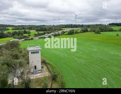 01 settembre 2023, Sassonia, Heinersgrün: La torre di confine di Heinersgrün, recentemente ristrutturata, nella regione del Vogtland, una volta parte della striscia della morte sul confine interno-tedesco (vista aerea con drone). Il testimone in pietra del regime di frontiera della DDR servirà in futuro come filiale del Museo tedesco-tedesco Mödlareuth e sarà aperto ai visitatori per visite. La torre era entrata in funzione nel 1978 come cosiddetto posto di comando. È una delle ultime reliquie della sicurezza di frontiera della RDT tra Sassonia e Baviera. Foto: Jan Woitas/dpa Foto Stock