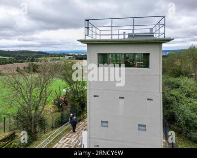 01 settembre 2023, Sassonia, Heinersgrün: La torre di confine di Heinersgrün, recentemente ristrutturata, nella regione del Vogtland, una volta parte della striscia della morte sul confine interno-tedesco (vista aerea con drone). Il testimone in pietra del regime di frontiera della DDR servirà in futuro come filiale del Museo tedesco-tedesco Mödlareuth e sarà aperto ai visitatori per visite. La torre era entrata in funzione nel 1978 come cosiddetto posto di comando. È una delle ultime reliquie della sicurezza di frontiera della RDT tra Sassonia e Baviera. Foto: Jan Woitas/dpa Foto Stock