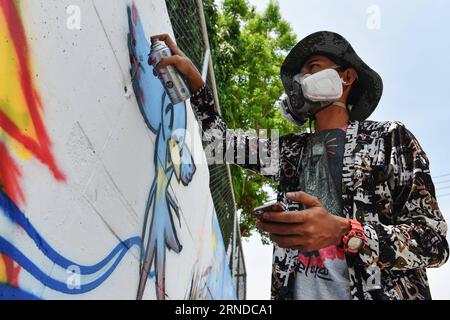 (160515) -- NAKHON SAWAN, 15 maggio 2016 -- Un artista di strada spruzza vernice sui suoi graffiti all'esterno di un impianto locale di trattamento delle acque reflue nella città di Nakhon Sawan, nella Thailandia centrale, il 15 maggio 2016. Oltre sessanta artisti di strada provenienti da tutta la Thailandia sono stati invitati dal governo municipale al Nakhon Sawan Street Art Project dal 13 al 15 maggio. Nel giro di tre giorni, gli artisti sono riusciti a trasformare le pareti esterne vuote di un impianto locale di trattamento delle acque reflue in una galleria di graffiti che si estende per circa 400 metri. ) THAILANDIA-NAKHON SAWAN-CULTURA POP-STREET ART-GRAFFITI Foto Stock