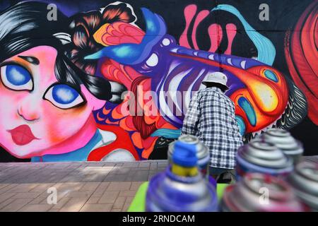 (160515) -- NAKHON SAWAN, 15 maggio 2016 -- Un artista di strada spruzza vernice sui suoi graffiti all'esterno di un impianto locale di trattamento delle acque reflue nella città di Nakhon Sawan, nella Thailandia centrale, il 15 maggio 2016. Oltre sessanta artisti di strada provenienti da tutta la Thailandia sono stati invitati dal governo municipale al Nakhon Sawan Street Art Project dal 13 al 15 maggio. Nel giro di tre giorni, gli artisti sono riusciti a trasformare le pareti esterne vuote di un impianto locale di trattamento delle acque reflue in una galleria di graffiti che si estende per circa 400 metri. ) THAILANDIA-NAKHON SAWAN-CULTURA POP-STREET ART-GRAFFITI Foto Stock