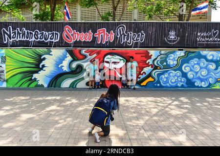 (160515) -- NAKHON SAWAN, May 15, 2016 -- Locals pose for photos with a newly-completed graffiti work outside a waste water treatment plant in the city of Nakhon Sawan in central Thailand, on May 15, 2016. Over sixty street artists from all over Thailand have been invited to the Nakhon Sawan Street Art Project by the municipal government from May 13 to 15. Within three days, the artists have succeeded in turing the blank outer walls of a local waste water treatment plant into a graffiti gallery that stretches for about four hundred meters. ) THAILAND-NAKHON SAWAN-POP CULTURE-STREET ART-GRAFFIT Stock Photo