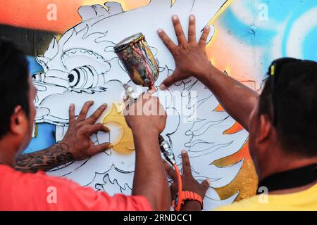 (160515) -- NAKHON SAWAN, May 15, 2016 -- Street artists use a stencil to complete their graffiti work outside a local waste water treatment plant in the city of Nakhon Sawan in central Thailand, on May 15, 2016. Over sixty street artists from all over Thailand have been invited to the Nakhon Sawan Street Art Project by the municipal government from May 13 to 15. Within three days, the artists have succeeded in turing the blank outer walls of a local waste water treatment plant into a graffiti gallery that stretches for about four hundred meters. ) THAILAND-NAKHON SAWAN-POP CULTURE-STREET ART- Stock Photo