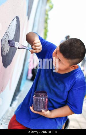 (160515) -- NAKHON SAWAN, May 15, 2016 -- A boy helps with a graffiti work outside a local waste water treatment plant in the city of Nakhon Sawan in central Thailand, on May 15, 2016. Over sixty street artists from all over Thailand have been invited to the Nakhon Sawan Street Art Project by the municipal government from May 13 to 15. Within three days, the artists have succeeded in turing the blank outer walls of a local waste water treatment plant into a graffiti gallery that stretches for about four hundred meters. ) THAILAND-NAKHON SAWAN-POP CULTURE-STREET ART-GRAFFITI LixMangmang PUBLICA Stock Photo