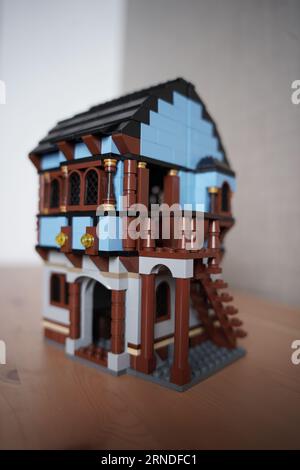 lego borgo medievale mercato 1601, Una persona sta costruendo una casa lego, villaggio lego allestito al mattino sul tavolo. Foto Stock