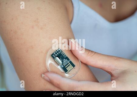 una ragazza applica un sensore elettronico di monitoraggio della salute alla sua mano Foto Stock