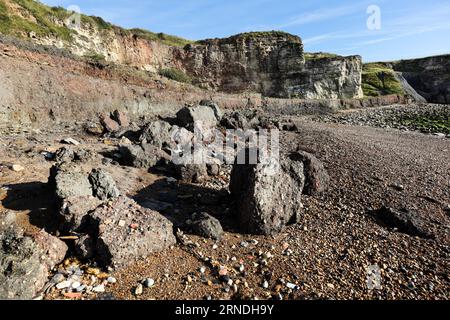 Strati di rifiuti di miniere di carbone e altri detriti industriali che vengono lentamente erosi e lavati via dal mare sulla Blast Beach, Durham Heritage Coast Foto Stock