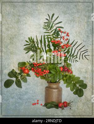 Autumn colorful rosehips and rowan berries with leaves in vase, artistic. Foto Stock