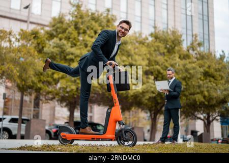 Affari pazzi, veloci e facili. Scooter consente agli uomini d'affari di essere efficienti e puntuali. Lo scooter elettrico offre una soluzione di trasporto facile e veloce Foto Stock