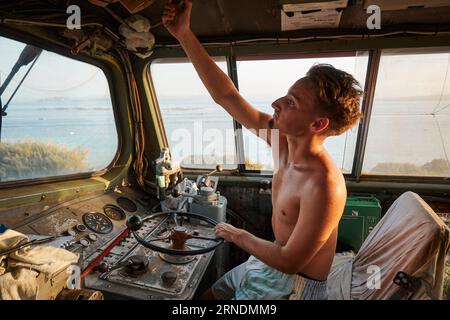 Un uomo caucasico nella cabina di guida di una grande locomotiva, che regola un componente sopra il finestrino Foto Stock